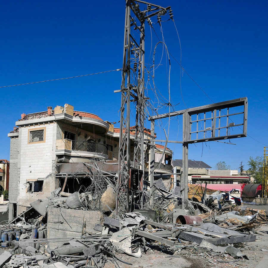 Ein Journalist, der eine Weste mit der Aufschrift "press" trägt, dokumentiert beschädigte Gebäude am Ort eines israelischen Luftangriffs im Dorf Temnin, Bekaa-Tal, Ostlibanon. © AP/dpa Foto: Hassan Ammar