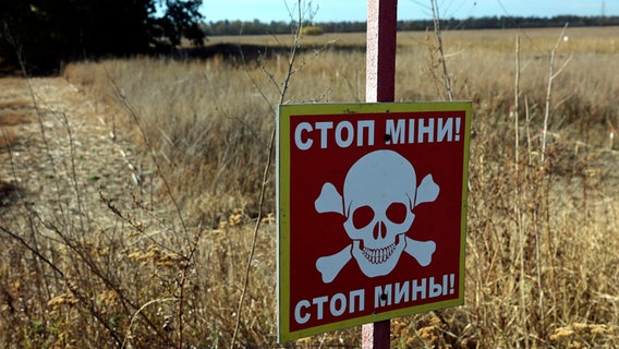 Ein Warnschild "Stop! Minen" ist in dem Bereich zu sehen, in dem die Entminung mit Hilfe modernster Technik durchgeführt wurde in der Region Charkiw (Ukraine). © Ukrinform/dpa 