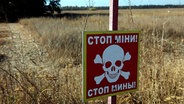 Ein Warnschild "Stop! Minen" ist in dem Bereich zu sehen, in dem die Entminung mit Hilfe modernster Technik durchgeführt wurde in der Region Charkiw (Ukraine). © Ukrinform/dpa 