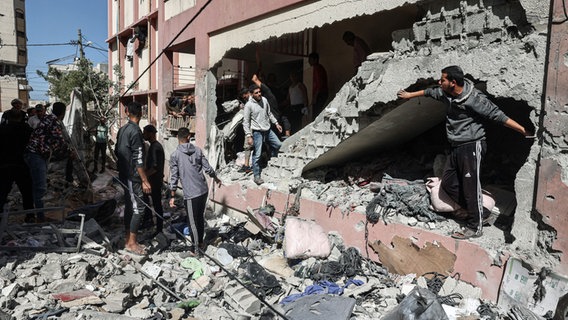 Menschen begutachten die Shuhada-Schule in Nuseirat (Gazastreifen), die von einem israelischen Luftangriff getroffen wurde. © APA Images via ZUMA Press Wire/dpa Foto: Omar Ashtawy Apaimages