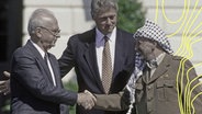 Jitzchak Rabin, Ministerpräsident von Israel, und Jassir Arafat, Vorsitzender der Palästinensischen Befreiungsorganisation, schütteln ihre Hände nach der Unterzeichnung eines Abkommens am 6. September 2015 vor den Augen von Bill Clinton. © Imago Images 