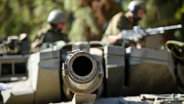 Israelische Soldaten arbeiten auf einem Merkava-Panzer in einer Stellung im Norden Israels an der Grenze zum Libanon. © Xinhua/dpa Foto: Ayal Margolin