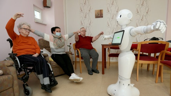 Ein programmierter Roboter führt Bewohnern eines Pflegezentrums Übungen vor. © dpa Foto: Matthias Bein