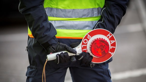 Ein Polizist hält Handschellen einsatzbereit vor einem Streifenwagen. © picture alliance / photothek | Florian Gaertner Foto: Florian Gaertner