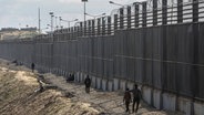 Palästinenser stehen an der Grenze zwischen dem Gazastreifen und Ägypten nahe Rafah. © AP Foto: Mohammed Talatene