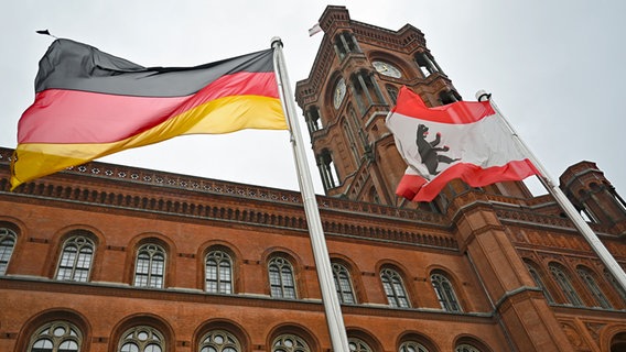 Das Rote Rathaus, Sitz der Regierenden Bürgermeisterin sowie des Senats von Berlin, im Vordergrund wehen eine Deutschland- und eine Berlin-Flagge. © dpa/dpa-Zentralbild Foto: Philipp Znidar