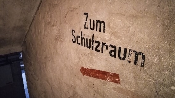 "Zum Schutzraum" steht an einer Wand im Keller eines Hauses. © greatif Foto: Marita Gaul