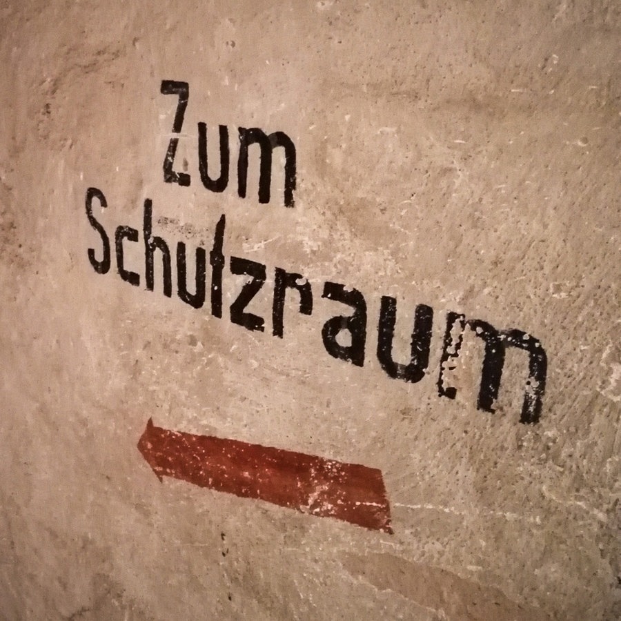 "Zum Schutzraum" steht an einer Wand im Keller eines Hauses. © greatif Foto: Marita Gaul