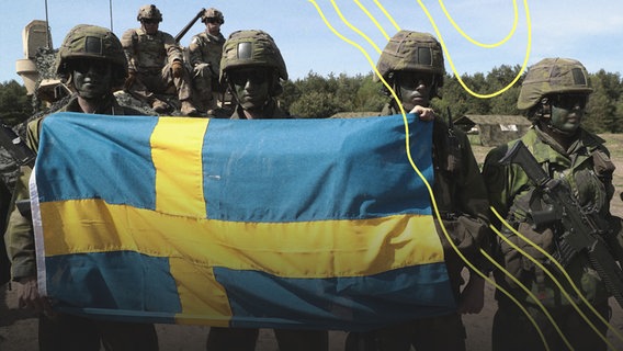 Schwedische Soldaten posieren auf dem Truppenübungsplatz mit einer schwedischen Flagge. © Imago Images 
