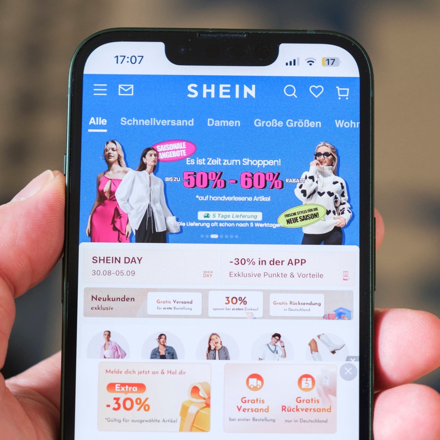 Hand hält Mobiltelefon auf der die Website des chinesischen Unternehmens Shein zu sehen ist. © Imago Foto: Guido Schiefer