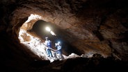 Die illegalen simbabwischen Goldgräber, Rooi Mpofu (rechts) und Sherphard Sibanda (links), klettern an einem alten Seil in eine stillgelegte Goldmine herunter. © dpa Foto: Kim Ludbrook