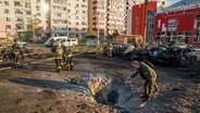 Einsatzkräfte der Feuerwehr betrachten den Krater nach einem russischen Luftangriff auf ein Wohnviertel in Sumy (Ukraine). © AP/dpa Foto: Evgeniy Maloletka