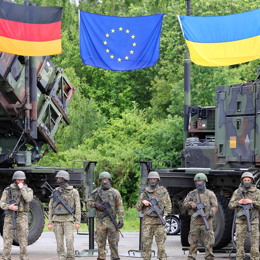 Deutsche und ukrainische Soldaten stehen beim Besuch des ukrainischen Präsidenten Selenskyj auf einem Truppenübungsplatz vor Flugabwehrraketensystemen vom Typ Patriot. © dpa Foto: Jens Büttner