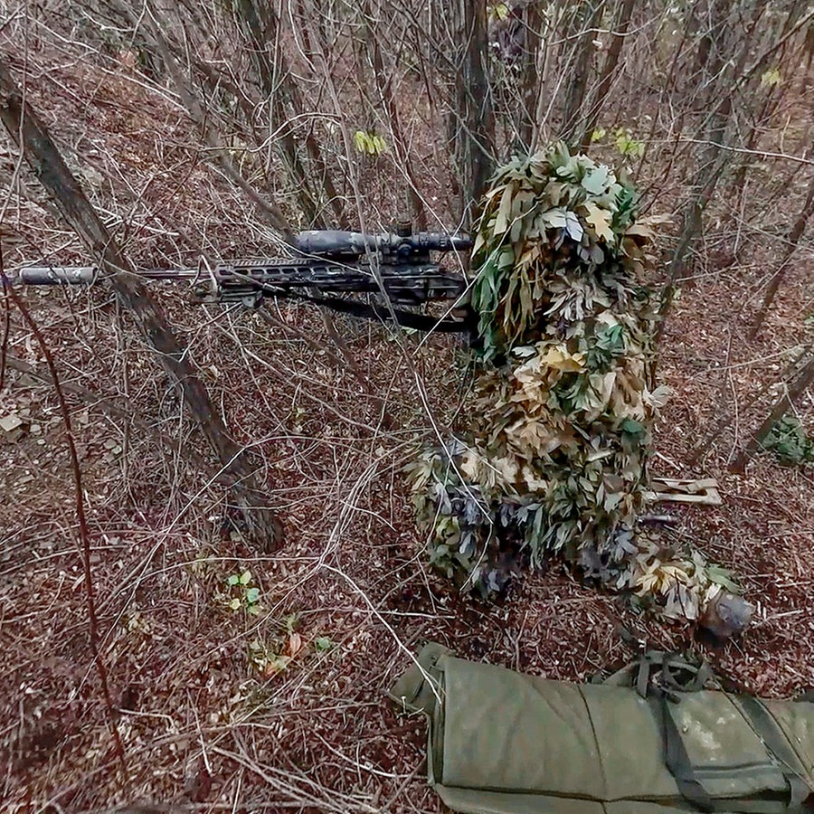 Ein gut getarnter russischer Scharfschütze feuert von einem nicht genannten Ort aus in Richtung der ukrainischen Streitkräfte. © Uncredited/Russian Defense Ministry Press Service via AP/dpa 