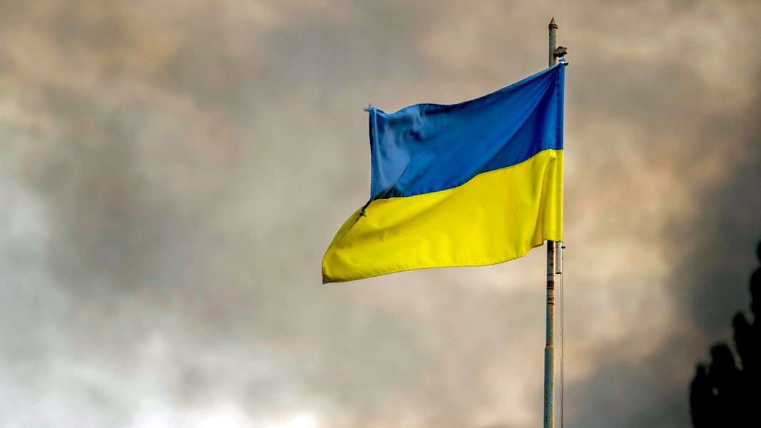 Die ukrainische Flagge ist vor dem Rauch eines Feuers zu sehen, nach russischen Angriffen auf Kiew. © ZUMA Press Wire/dpa Foto: Andreas Stroh