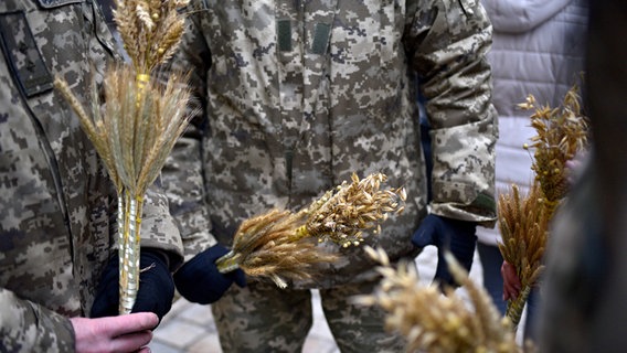 Ukrainische Soldaten halten kleine Sträuße aus Hafer und Roggen in den Händen. © Avalon Foto: Markiian Lyseiko