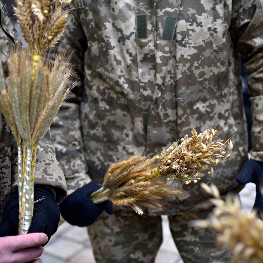 Ukrainische Soldaten halten kleine Sträuße aus Hafer und Roggen in den Händen. © Avalon Foto: Markiian Lyseiko