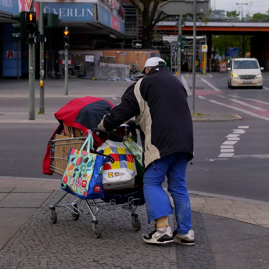 Ein Obdachloser geht im Berliner Stadtteil Steglitz mit seinen Habseligkeiten in einem Einkaufswagen über einen Gehweg. © picture alliance Foto: Wolfram Steinberg
