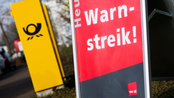 Ein Aufsteller mit der Aufschrift "Heute Warnstreik" steht neben einem Briefkasten der Deutschen Post. © Philipp von Ditfurth/dpa Foto: Philipp von Ditfurth