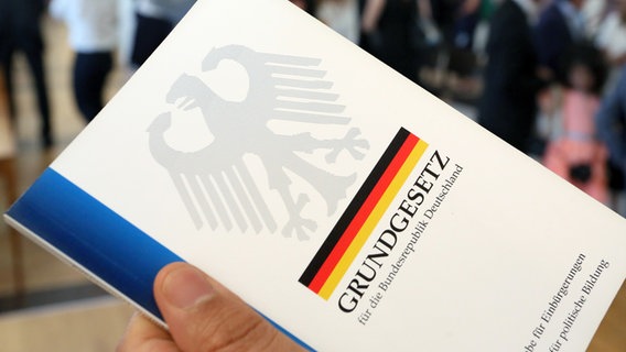 Eine Hand hält eine Ausgabe des Grundgesetzes der Bundesrepublik Deutschland. © dpa Foto: Stephanie Pilick