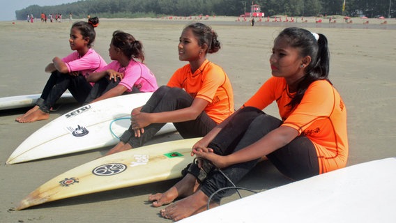 Mädchen sitzen mit ihren Surfboards am Strand. © NDR Info 