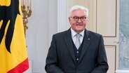 Ein Porträtbild zeigt Bundespräsident Frank-Walter Steinmeier stehend in seinem Amtszimmer neben der Bundesfahne. © dpa Foto: Bernd von Jutrczenka