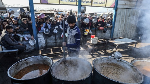 Im Gazastreifen versammeln sich Menschen, um Mahlzeiten von der Wohltätigkeitsküche (Tekka) in Rafah zu erhalten. © picture alliance/dpa | Abed Rahim Khatib 