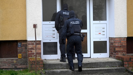 Beamte der Bundespolizei gehen in ein Wohnhaus unweit des Rostocker Ostseestadions. © dpa Foto: Philip Dulian