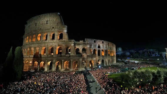 Rom: Menschen halten Kerzen vor dem Kolosseum während einer Fackelprozession auf der Via Crucis (Kreuzweg) am Karfreitag. © AP/dpa Foto: Andrew Medichini