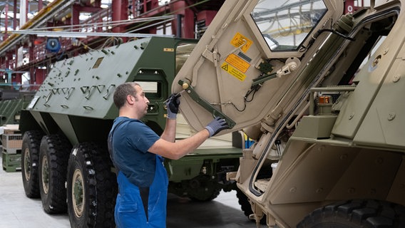 Ein Mitarbeiter von Rheinmetall arbeitet an einem Panzer vom Typ Fuchs in der Fertigungshalle von Rheinmetall © picture alliance/dpa Foto: Swen Pförtner