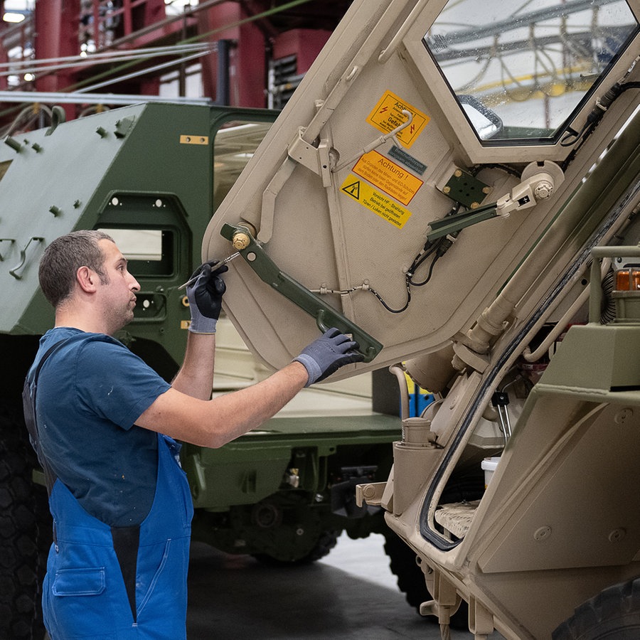 Ein Mitarbeiter von Rheinmetall arbeitet an einem Panzer vom Typ Fuchs in der Fertigungshalle von Rheinmetall © picture alliance/dpa Foto: Swen Pförtner