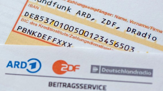 Ein Briefbogen des Beitragsservice und ein Überweisungsträger für den Rundfunkbeitrag liegen auf einem Tisch. © dpa bildfunk Foto: Sebastian Kahnert