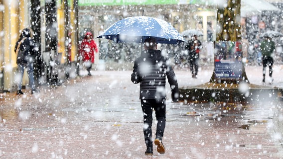 Ein Mann geht mit Schirm durch Schneeregen in Hamburg © Bodo Marks/dpa Foto: Bodo Marks