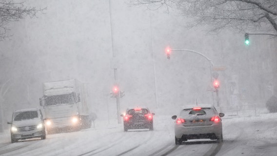 Fahrzeuge auf einer verschneiten Straße im Dämmerlicht. © dpa bildfunk 