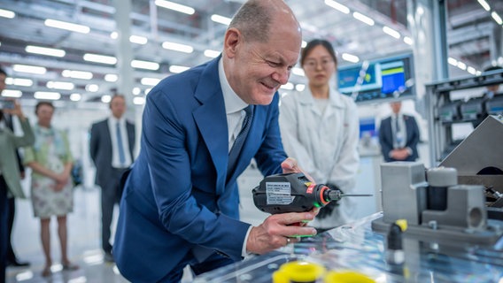 Bundeskanzler Olaf Scholz (SPD), besucht die Firma Bosch mit der Produktionsstätte von Wasserstoffantrieben in Chongqing in China und schraubt mit einem Akkuschrauber in der Fertigung. © Michael Kappeler/dpa 