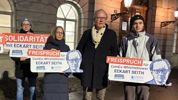 Rechtsanwalt Eckart Seith (2.v.r.) neben der ehemaligen Chefermittlerin im Cum-Ex-Komplex, Anne Brorhilker (M). Daneben Demonstraten, die Schilder mit der Aufschrift: "Freispruch für CumEx-Whistleblower Eckart Seith" und "Solidarität mit Eckart Seith" tragen © picture alliance/dpa Foto: Christiane Oelrich