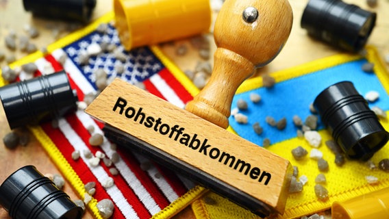 Stempel mit Aufschrift Rohstoffabkommen auf den Fahnen der USA und Ukraine mit Fässern und Steinen, Symbolfoto Rohstoff-Deal zwischen den USA und der Ukraine, Fotomontage © picture alliance / CHROMORANGE | Christian Ohde Foto: Christian Ohde