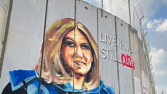 Ein gemaltes Porträt von Shireen Abu Akleh an einer Mauer mit Stacheldragt. Daneben der Schriftzug " LIVE NEWS STILL ALIVE" © ARD Foto: Bettina Meier