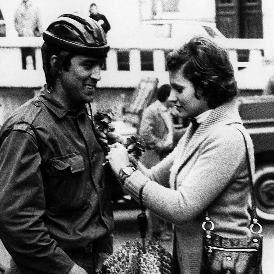 Eine Frau heftet am 25.04.1974 einem Soldaten in Lissabon, Portugal, eine rote Nelke an. Die rote Nelke ist das Symbol der portugiesischen Revolution. © Picture alliance Foto: Telimprensa