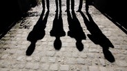 Vier Personen stehen auf einer gepflasterten Straße im Gegenlicht. © Mr. Nico / photocase.de Foto: Mr. Nico