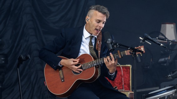 Ein Mann auf einer Bühne spielt Gitarre und singt in ein Mikrofon. © Picture Alliance / Markus Scholz Foto: Markus Scholz