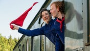 Zwei Jugendliche gucken aus dem Zug und schwenken eine Fahne. © LOOKSfilm 