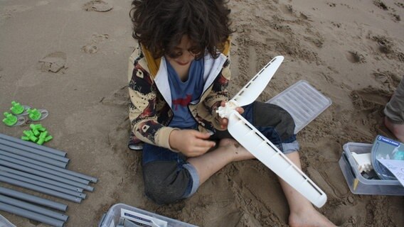 Zwei junge Kinder sitzen im Sand und bauen ein Windrad. © NDR Mikado/Sahin 