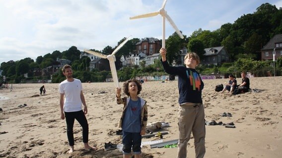 Zwei junge Kinder stehen am Strand und halten Windräder in die Luft. © NDR Mikado/Sahin 