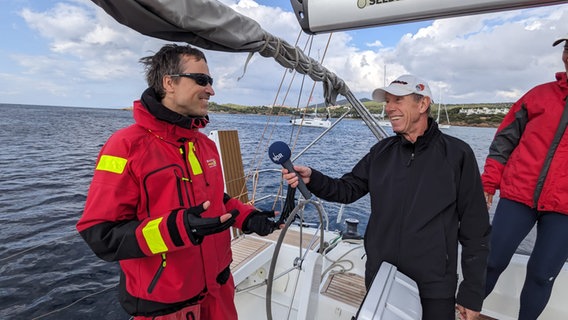 Ein lächelnder Reporter interviewed einen Skipper auf einer Jacht in der Ägäis © NDR Foto: Carsten Vick