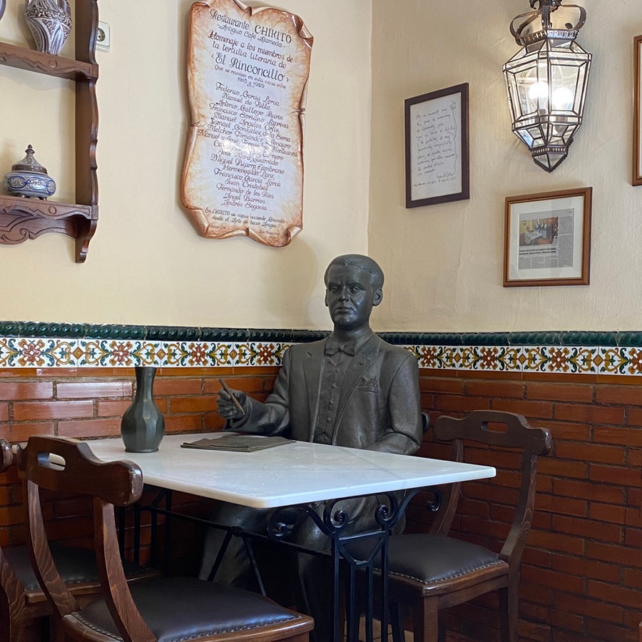 Eine Bronzefigur sitzt in einem traditionallem Restaurant in Granada - die Figur stellt den Dichter Federico García Lorca dar © NDR Foto: Tom Noga