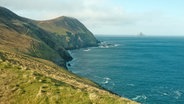 Ein Stück Küste von Irland, beschienen von der Sonne, voller schroffer Felsen, blauem Meer, und weißen Wolken © NDR Foto: Matthias Schuch