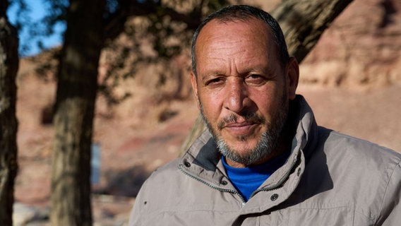 Ein Mann mit Bart, grauer Jacke und blauem Shirt lächelt, dahinter sind unscharf Bäume zu erkennen © NDR / Florian Guckelsberger Foto: Florian Guckelsberger