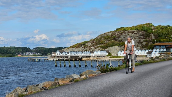 Ein Mann fährt Fahrrad am Rande des Meeres in Schweden © NDR Foto: Ulrike Keding