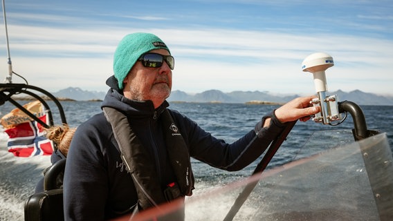 Ein Mann fährt ein Speedboot durch einen Fjord, trägt eine Sonnenbrille © NDR Foto: Marco Schulze / Johannes Koch